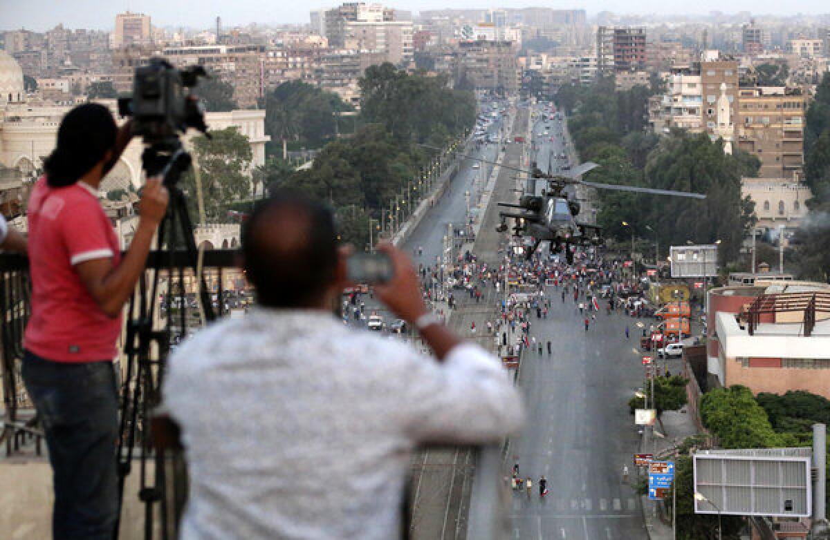 Journalists film an Egyptian military helicopter as it flies by the presidential palace in Cairo on July 5, 2013.