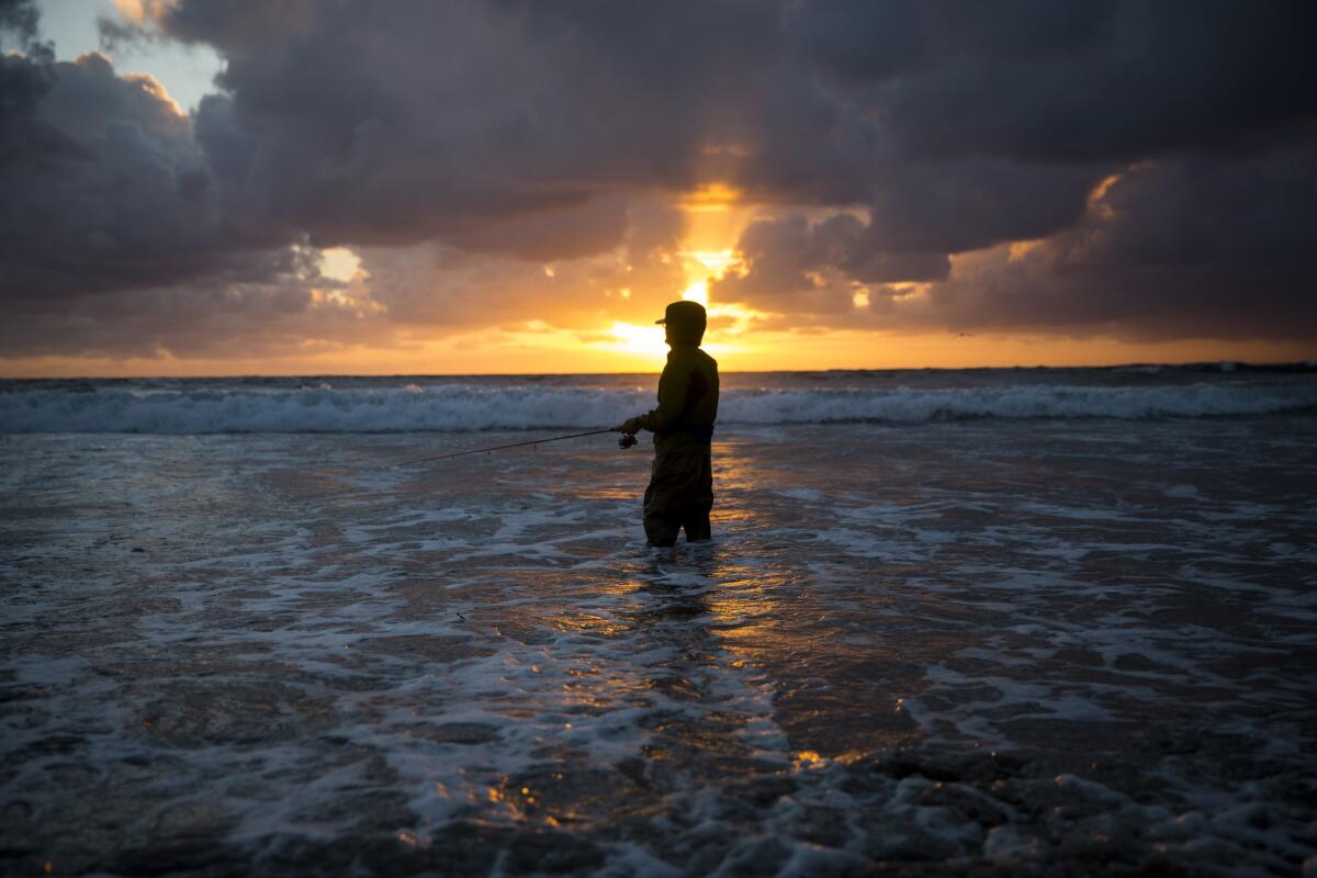 Diamond Bar resident Steve Kang fishes in the surf of Manhattan Beach as the sun sets Monday.
