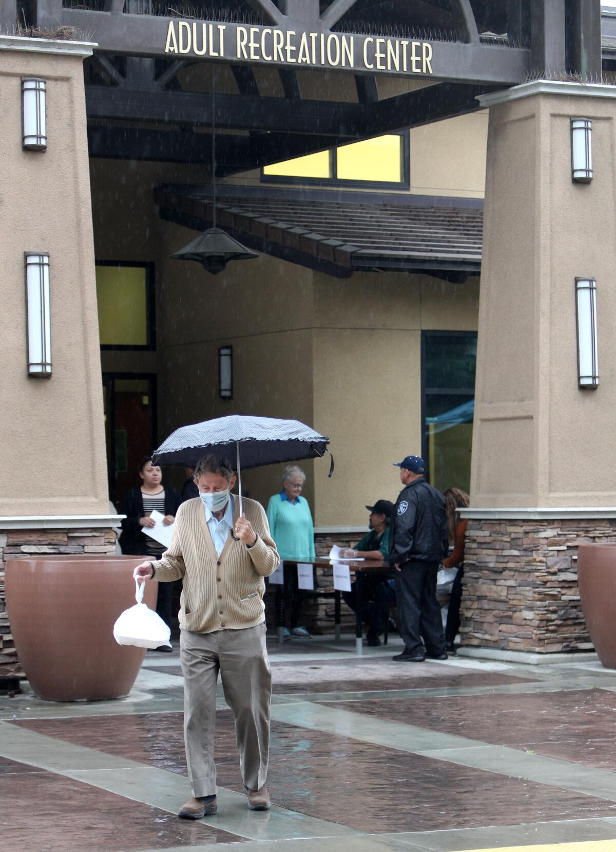 Clad in a surgical face mask 92-year-old George Wardas walks away from Glendale's Adult Recreation Center with his meal from the elderly nutrition program.