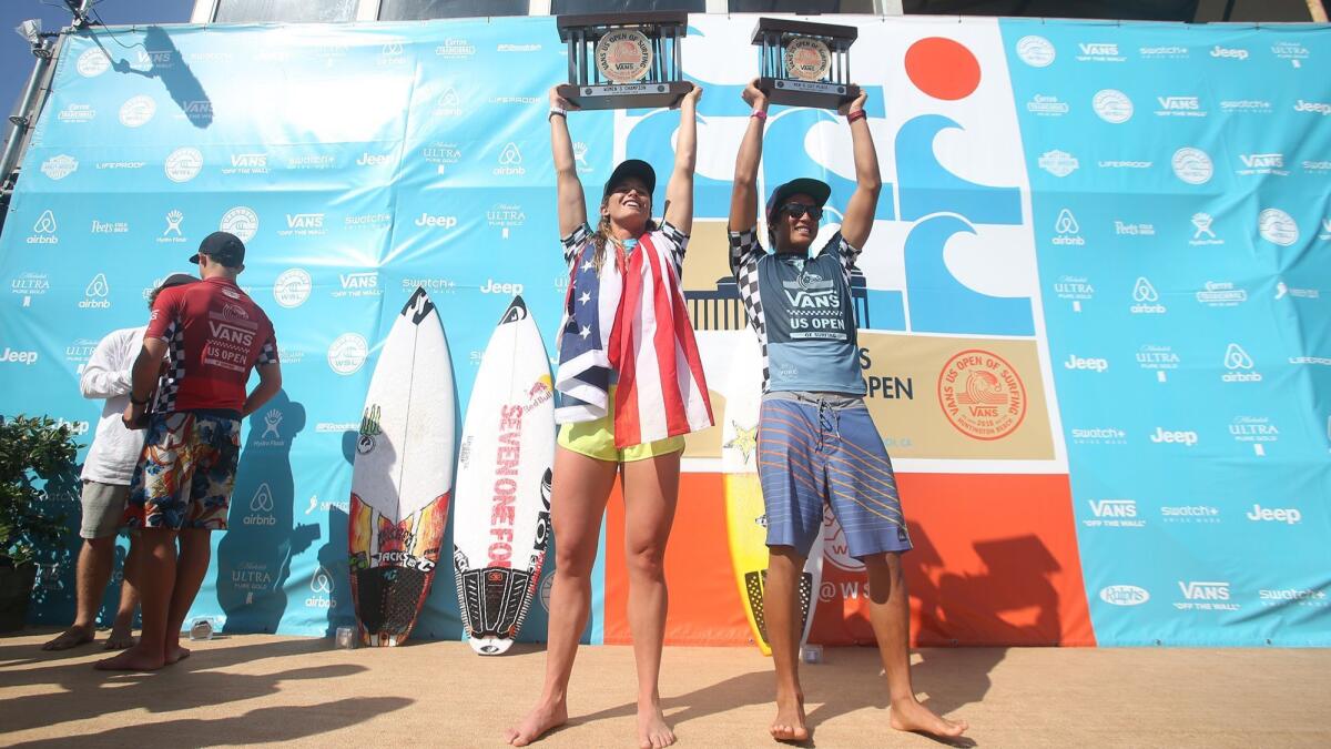 Surfing locals Courtney Conlogue and Kanoa Igarashi hold up their first-place trophies 