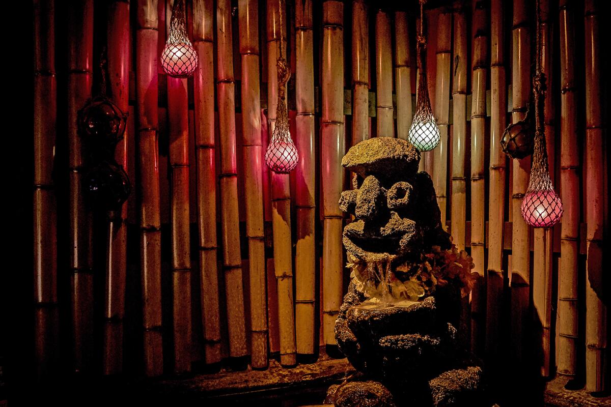 A carved tiki and colorful glass fishing weight lights at the Tonga Hut tiki bar.
