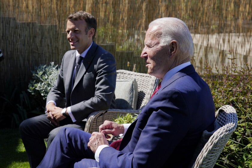 President Biden and French President Emmanuel Macron seated outdoors.