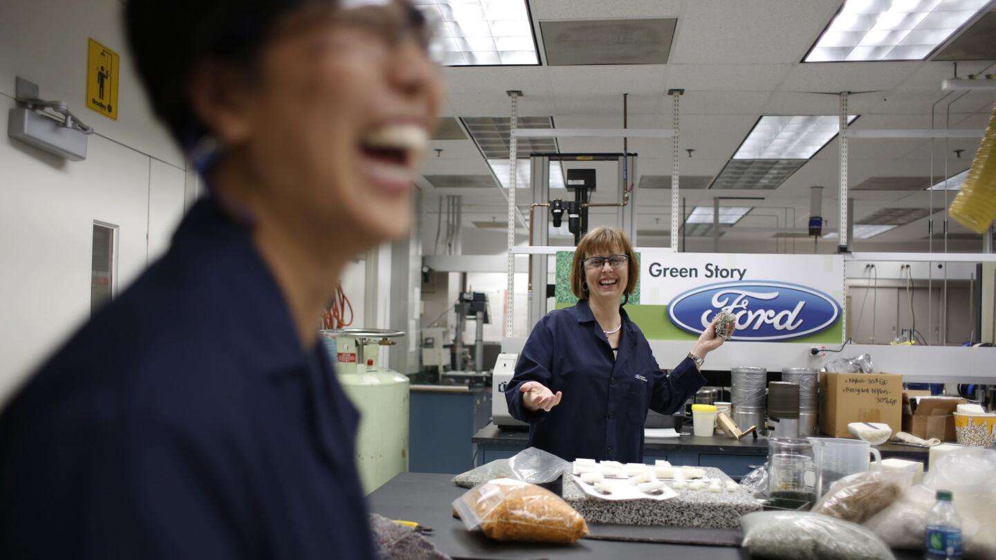 Deborah Mielewski, right, winds up to toss a handful of shredded money at Ellen Lee in Ford's Sustainable Materials Lab in Dearborn, Mich.