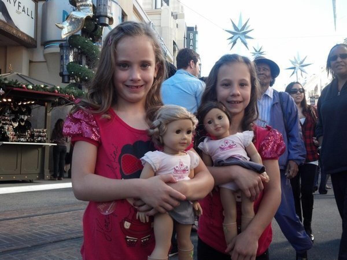 Kaitlyn and Kristin Welch hold their new American Girl dolls, an early Christmas and birthday gift from their mother and grandmother, at the Grove shopping center.