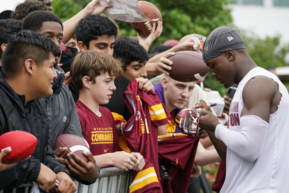 Washington Commanders wide receiver Terry McLaurin, right, signs autographs for fans after practice during NFL football training camp Monday, Aug. 15, 2022, in Ashburn, Va. (AP Photo/Alex Brandon)