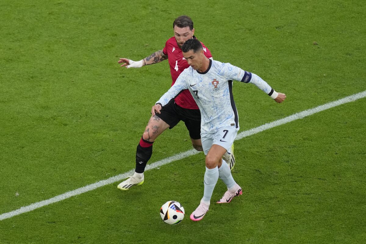 El portugués Cristiano Ronaldo pelea por el balón ante Guram Kashia de Georgia