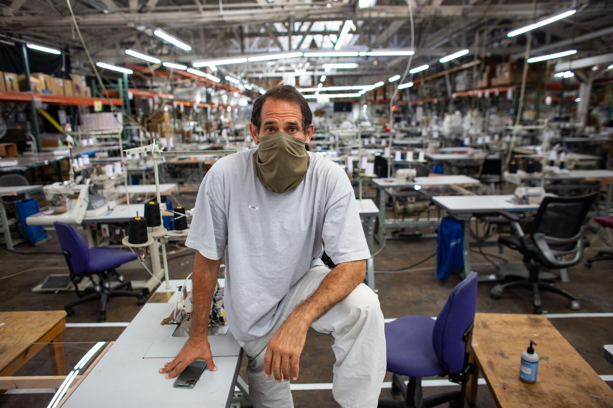 Dov Charney in a face covering in a room with tables and chairs behind him.