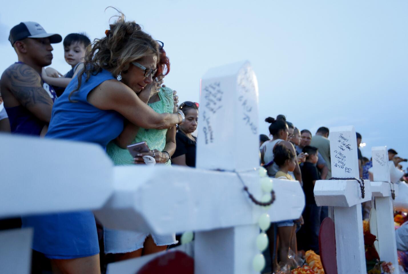Rebecca Najera, left, hugs Elsa Escobar as they joined others gathered Monday, Aug. 5, 2019 in front of crosses representing the victims who died in the shooting at a Walmart in El Paso, Texas. (Vernon Bryant/The Dallas Morning News/TNS) ** OUTS - ELSENT, FPG, TCN - OUTS **