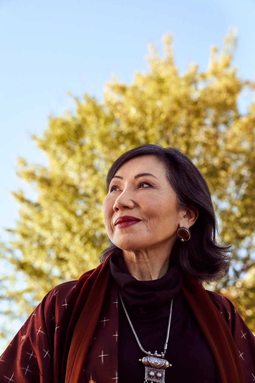 Amy Tan stands in front of a tree