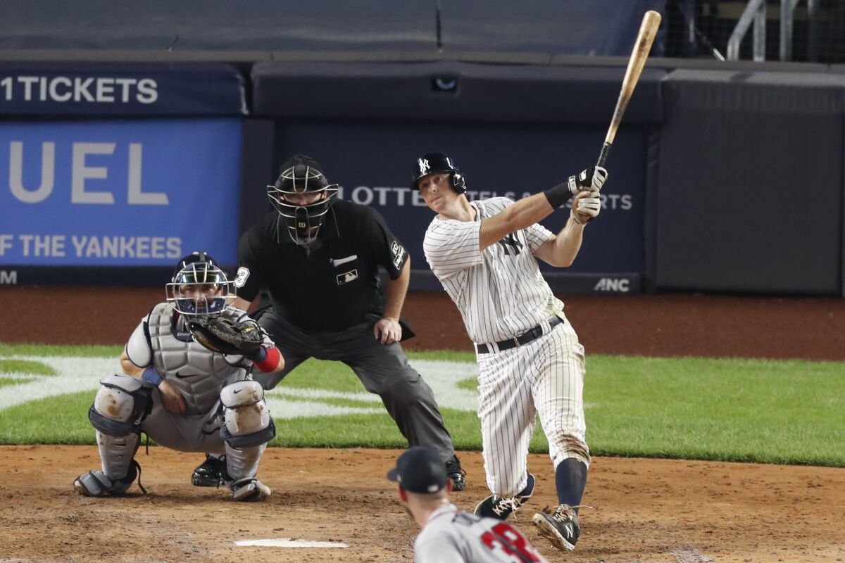 New York Yankees DJ LeMahieu, right, hits an RBI single during the fifth inning of a baseball game against the Atlanta Braves, Wednesday, Aug. 12, 2020, in New York. Braves catcher Travis d'Arnaud, left, and home plate umpire Todd Ticheonor watch. Braves pitcher Josh Tomlin is on the mound (AP Photo/Kathy Willens)