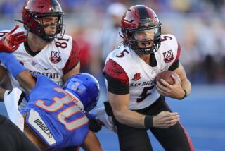 San Diego State quarterback Braxton Burmeister (5) runs around the block by tight end Mark Redman (81) on Boise State linebacker Isaiah Bagnah (30) during the first half of an NCAA college football game Friday, Sept. 30, 2022, in Boise, Idaho. (AP Photo/Steve Conner)