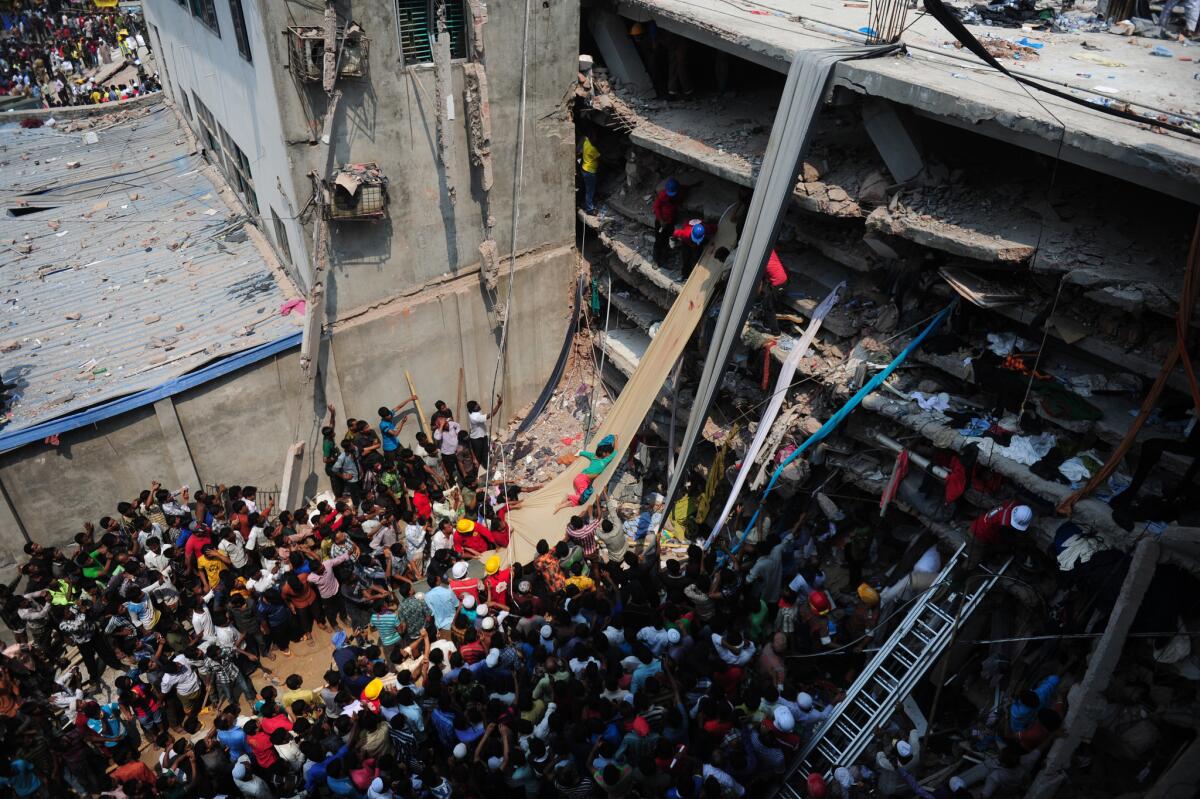 Volunteers use a length of cloth as a slide to move victims recovered from the rubble after a building collapsed on the outskirts of Dhaka, Bangladesh.