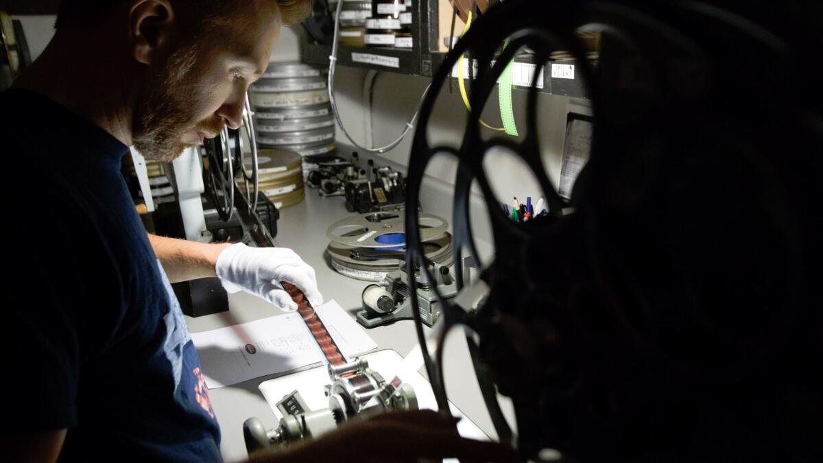 New Beverly Cinema archivist Aaron Martz inspects a film to make sure it's not damaged and is ready for its next screening.