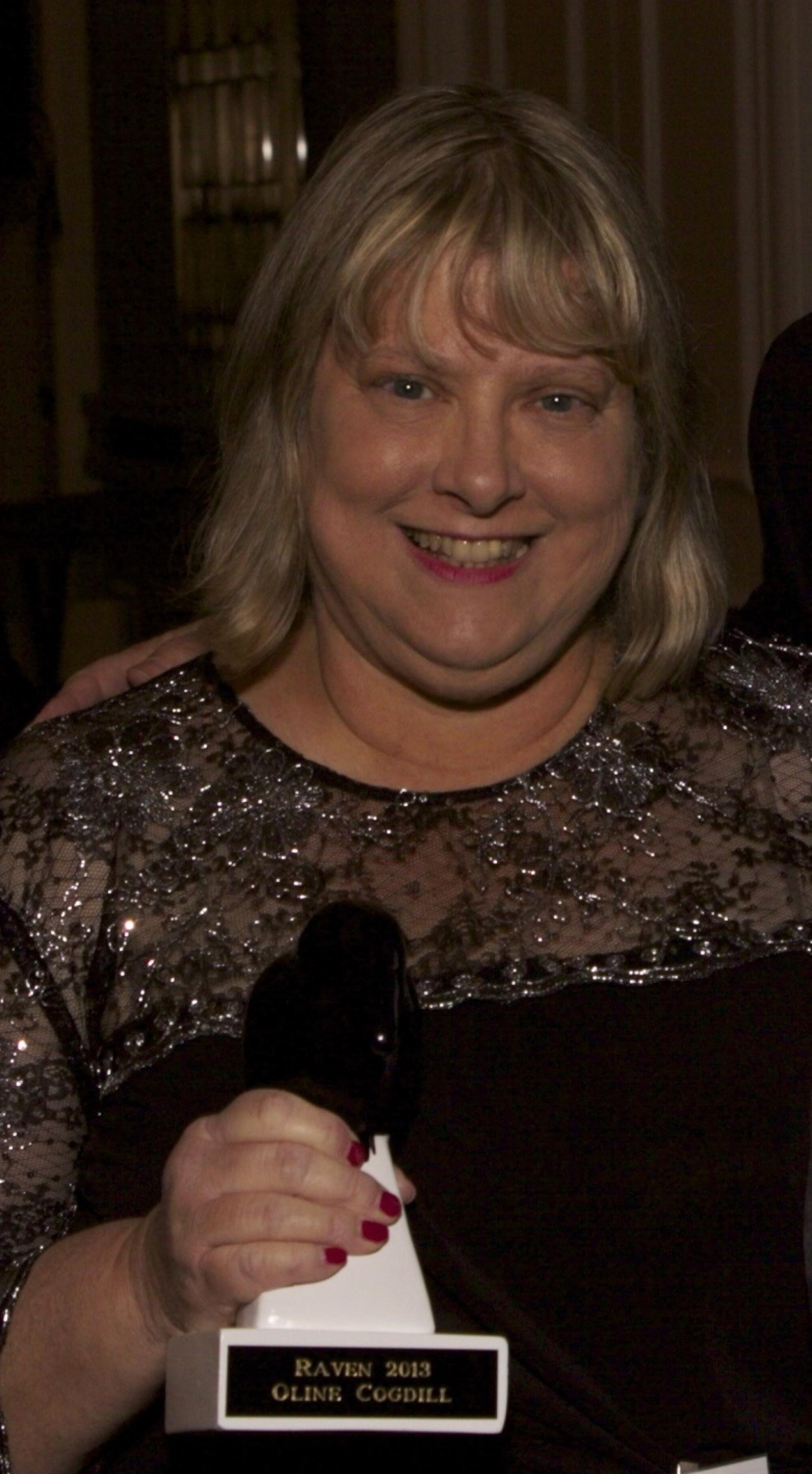 A woman holding a Raven Award statuette.