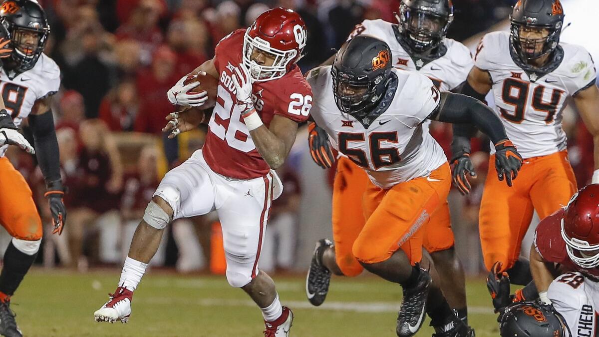 Oklahoma running back Kennedy Brooks (26) runs the ball ahead of Oklahoma State defensive tackle Enoch Smith Jr. (56) in the second half on Saturday.
