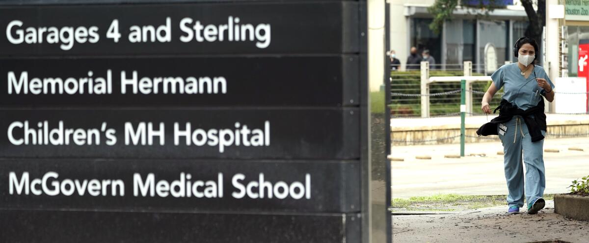 A healthcare worker wearing scrubs walks through the Texas Medical Center in Houston. It's seeing a COVID-19 spike.