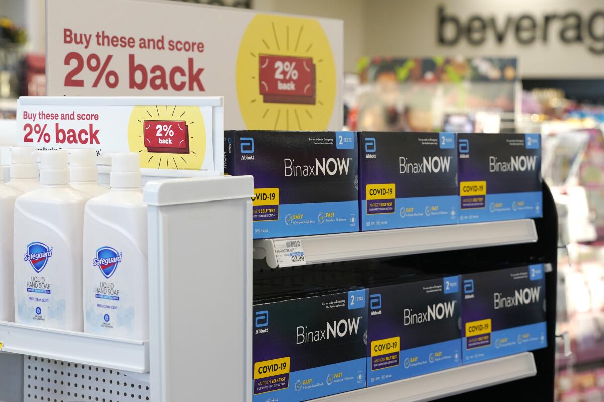 Boxes of rapid coronavirus tests are displayed for sale next to liquid hand soap at a drugstore. 