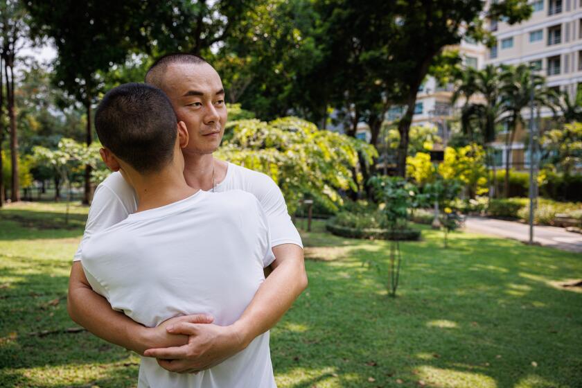 Bangkok, Thailand-May 5, 2024-Jeffery Hu hugs his boyfriend, Wilfred Wu, in Santiphap Park after an outdoor workout on May 5, 2024 in Bangkok, Thailand. Jeffrey Hu, a 34-year-old Chinese teacher, lived in Thailand after college but returned to China during the pandemic, which solidified his decision to permanently leave; upon his return to Thailand in August 2023, he works freelance in the tourism industry as a guide and occasional Chinese teacher, feeling comfortable being himself in Thailand but nervous about its proximity to China as a political activist, planning eventually to relocate to the U.S. with his boyfriend Wilfred Wu. Amid Thailand's progressive strides in LGBTQ rights, notably the recent legalization of same-sex marriage, Bangkok has become an increasingly alluring destination for LGBTQ individuals from China. Departing their home country, where despite the decriminalization of homosexuality, the space for LGBTQ advocacy and expression has dwindled. Attracted by Pride events, inclusivity, and investment prospects, many young Chinese are buying in properties in Bangkok. Photo by Lauren DeCicca for The Los Angeles Times