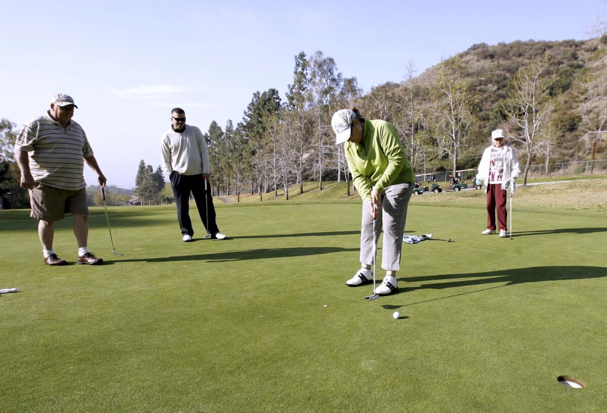 Sandra Pessaro puts one as, from left, Ed Pape, Joaquin Herbozo and Jeannie Smith look on at the 10th Annual Guys and Dolls Golf Tournament at DeBell Golf Club in Burbank on Thursday, March 15, 2012.