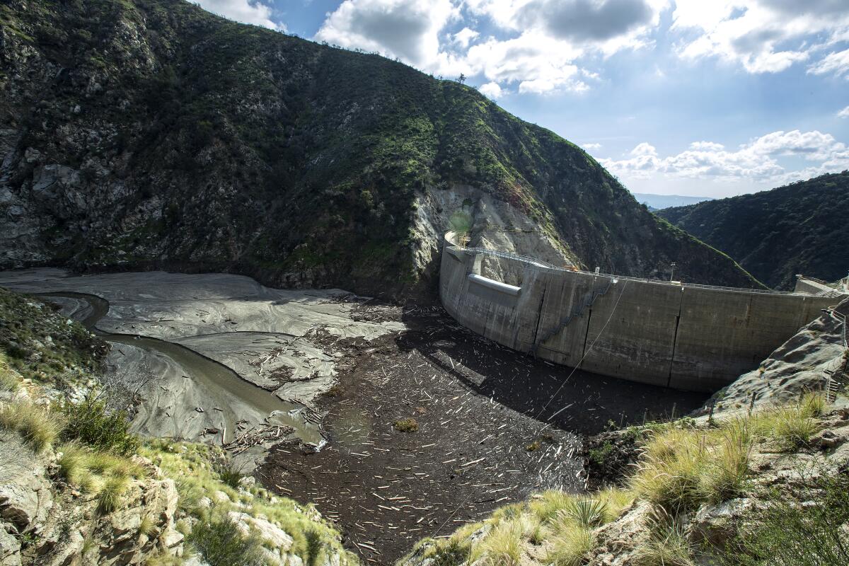 A dam, surrounded by mountains, holds back a collection of mud and debris.