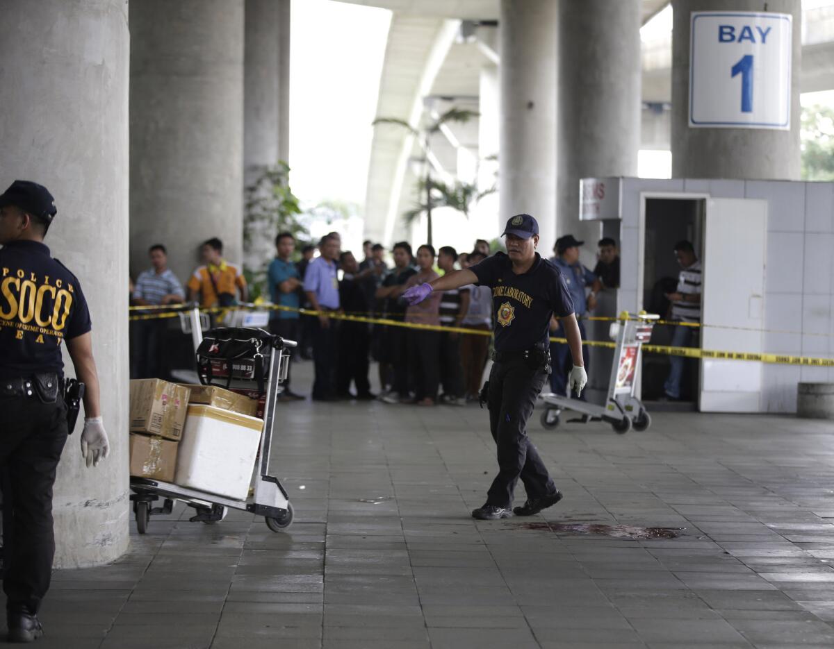 Police investigators examine the scene of an ambush at Manila's Ninoy Aquino International Airport that killed four people, including the mayor of a troubled southern town.