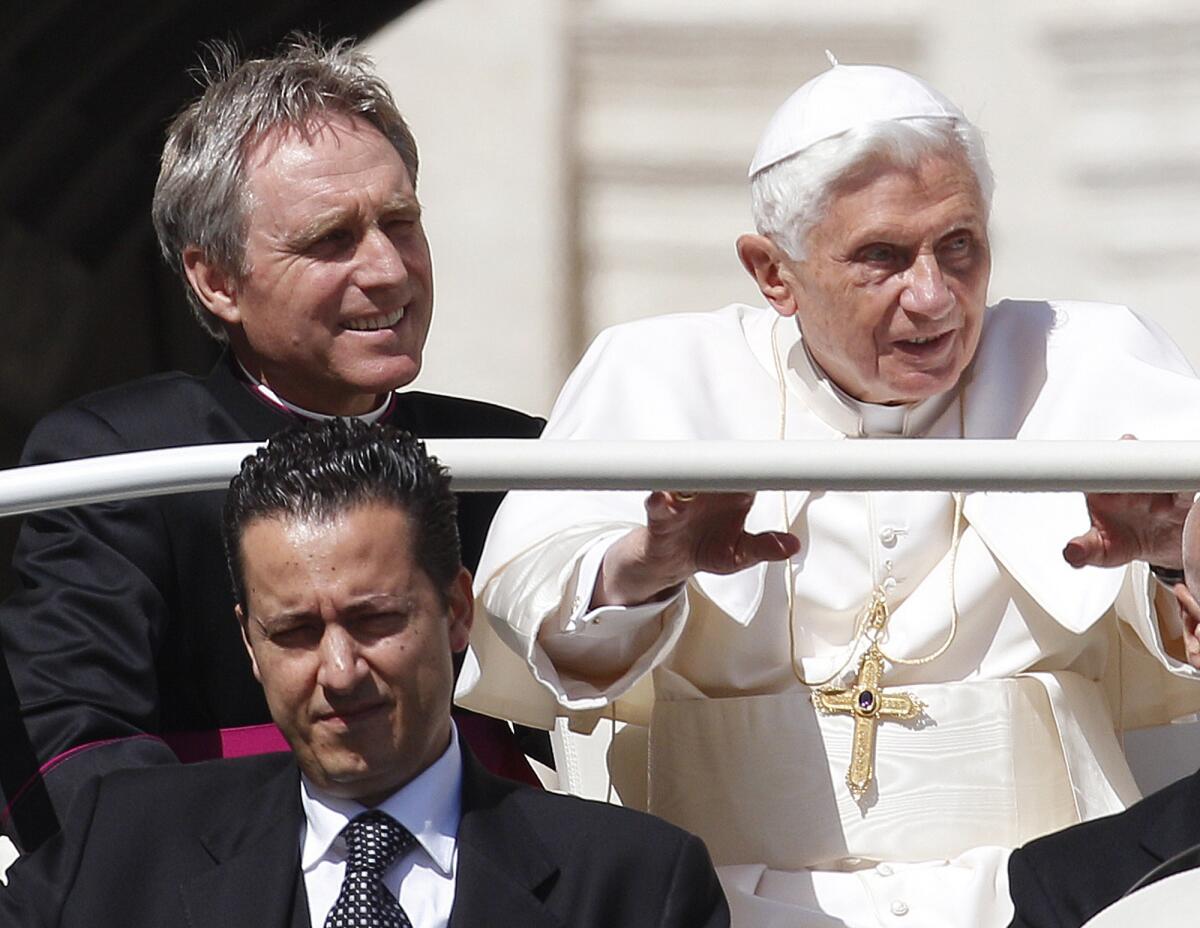 Pope Benedict XVI rides in the Popemobile with his personal secretary and his butler in 2012.