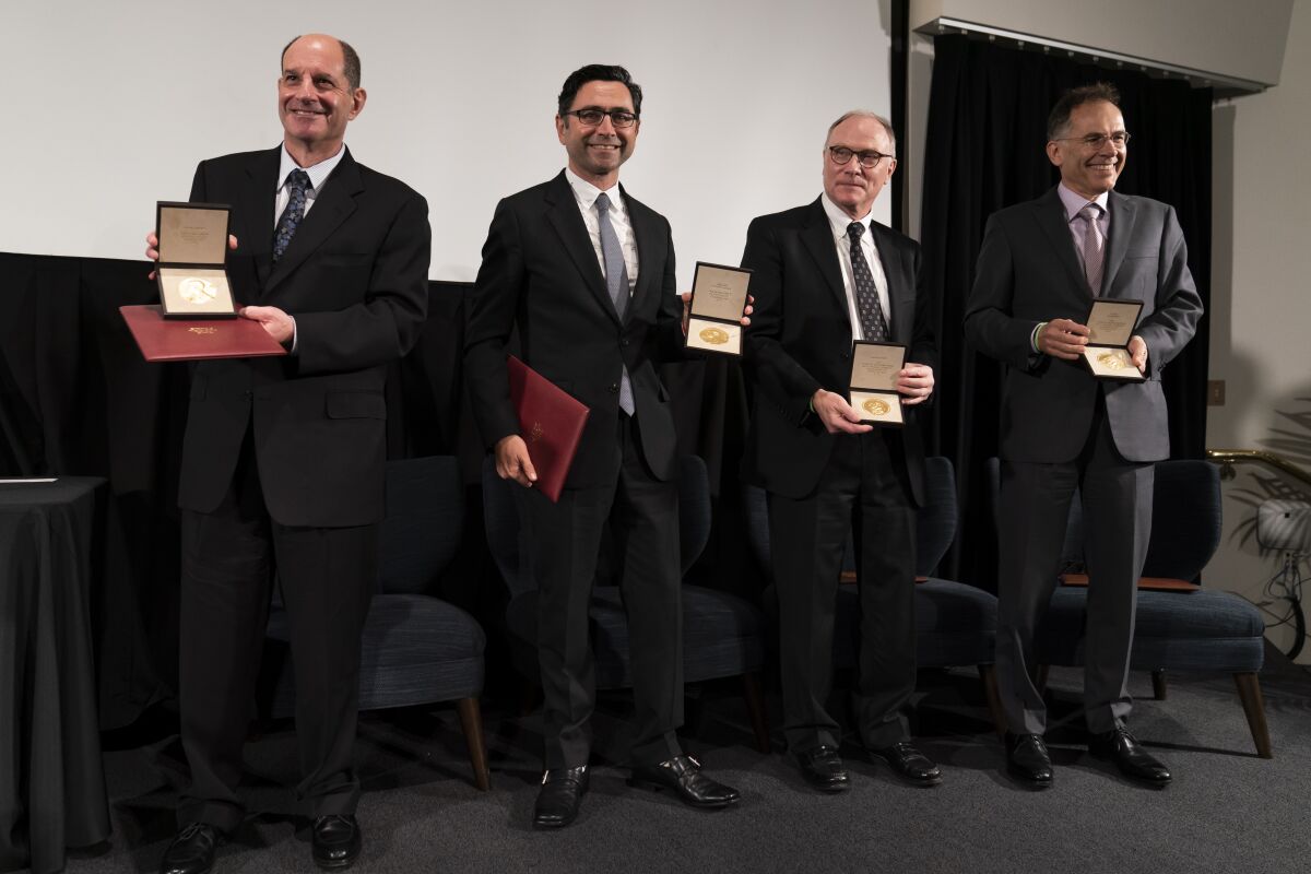 The 2021 Nobel Prize laureates David Julius, from left, Ardem Patapoutian, David Card and Guido W. Imbens pose with their medals during a ceremonial presentation Wednesday, Dec. 8, 2021, in Irvine, Calif. (AP Photo/Jae C. Hong)
