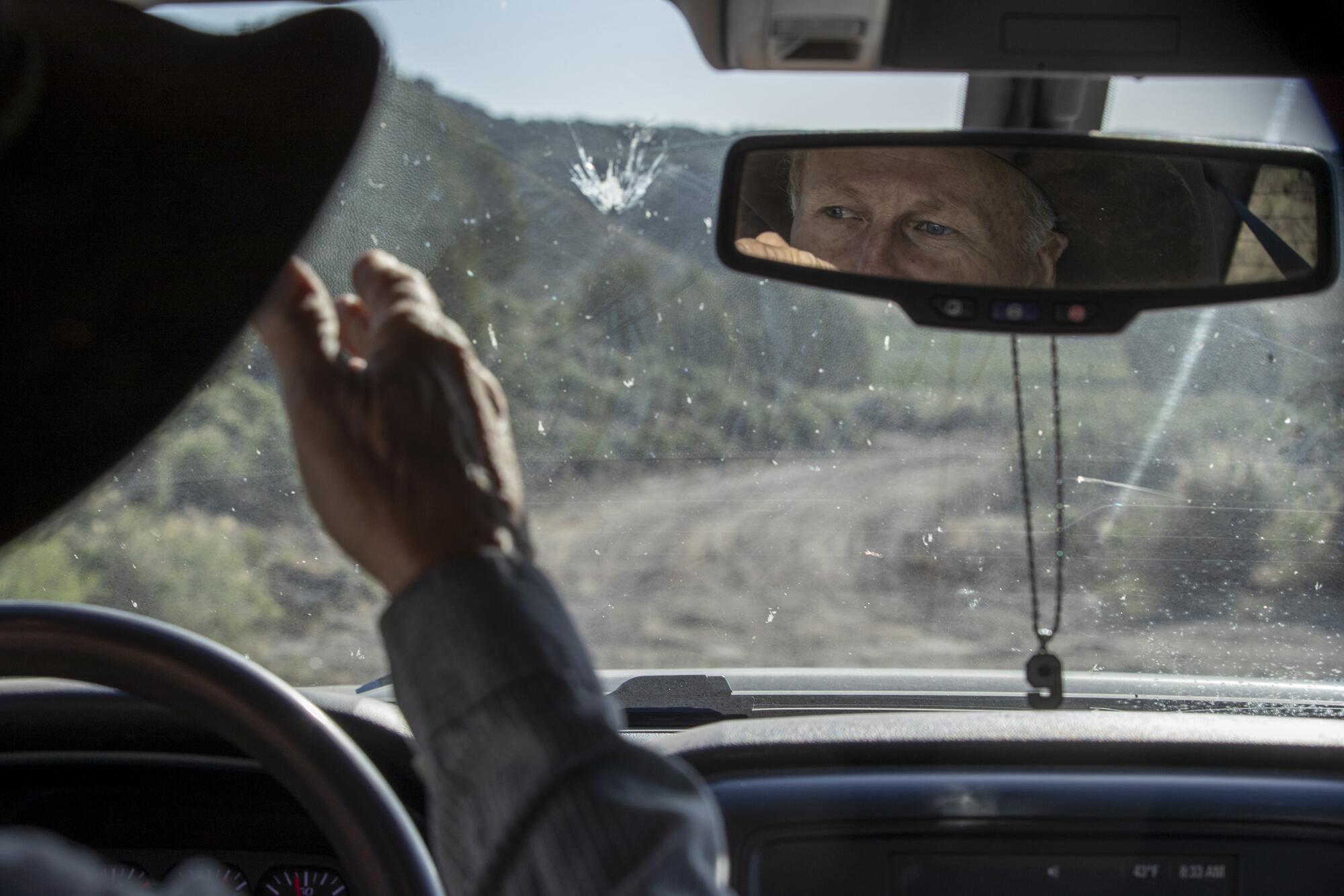 A pendant hangs from the rearview mirror of a pickup truck.