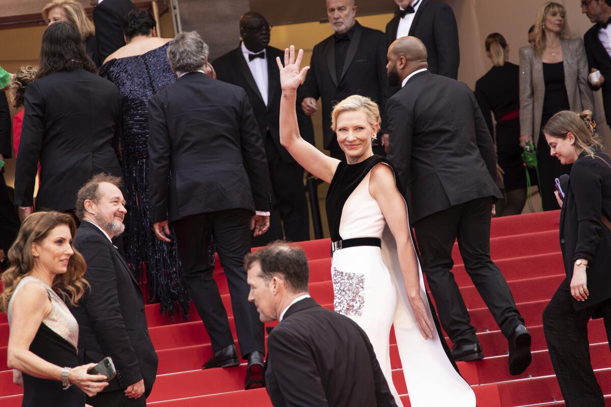 Cate Blanchett waving with her right arm on the red carpet in Cannes.