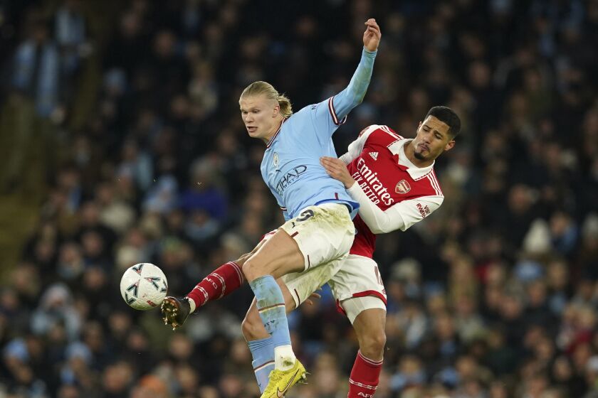 Manchester City's Erling Haaland, left, challenges for the ball with Arsenal's William Saliba during the English FA Cup 4th round soccer match between Manchester City and Arsenal at the Etihad Stadium in Manchester, England, Friday, Jan. 27, 2023. (AP Photo/Dave Thompson)