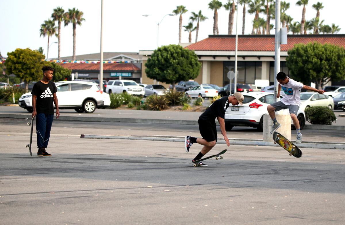 Skateboarders play in a parking lot on the 6900 block of Warner Avenue in Huntington Beach on Friday, Aug. 21, 2020.