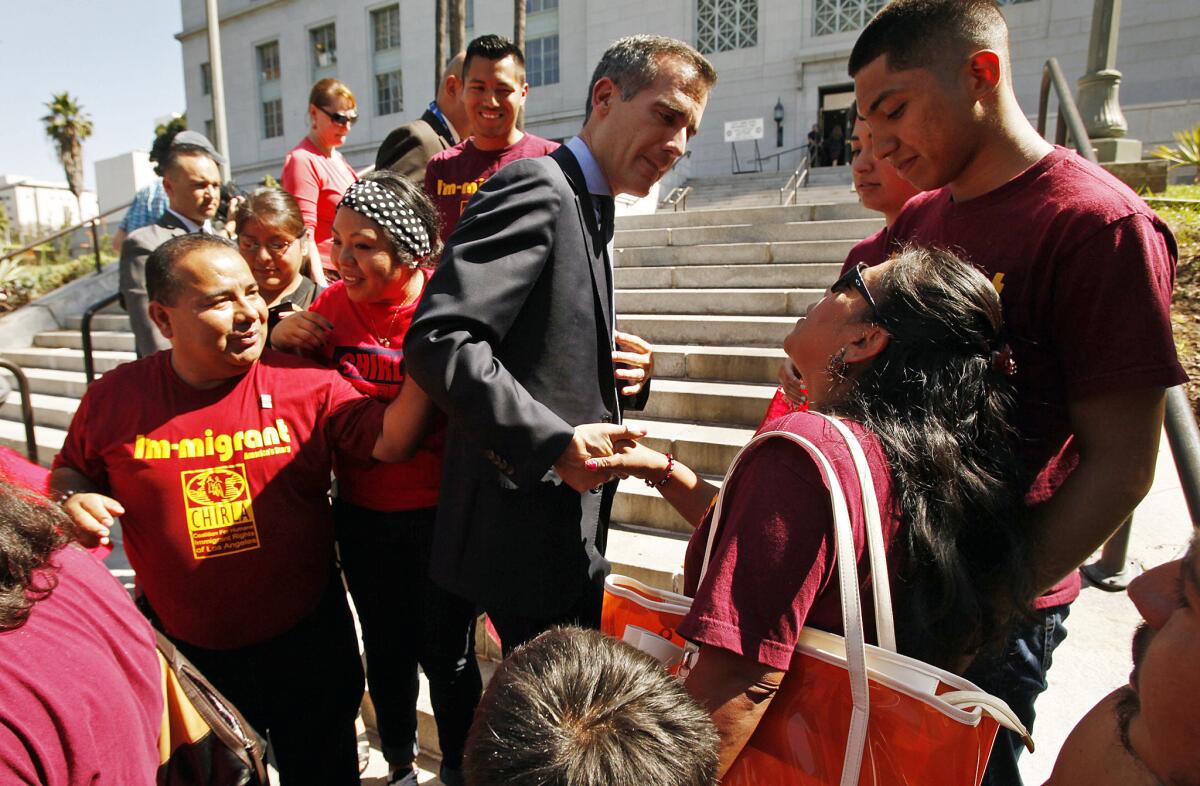 Los Angeles Mayor Eric Garcetti, center, shakes hands with supporters on the steps of City Hall after he and Los Angeles Police Chief Charlie Beck announced in July that the LAPD would no longer comply with requests from federal immigration officials to detain some suspects.