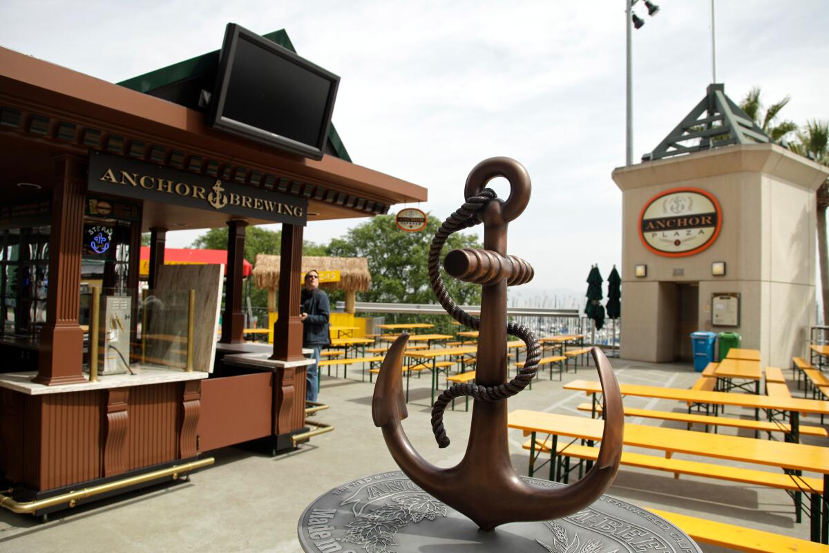 Picnic tables and an anchor statue outside a stand with a sign reading "Anchor Brewing"