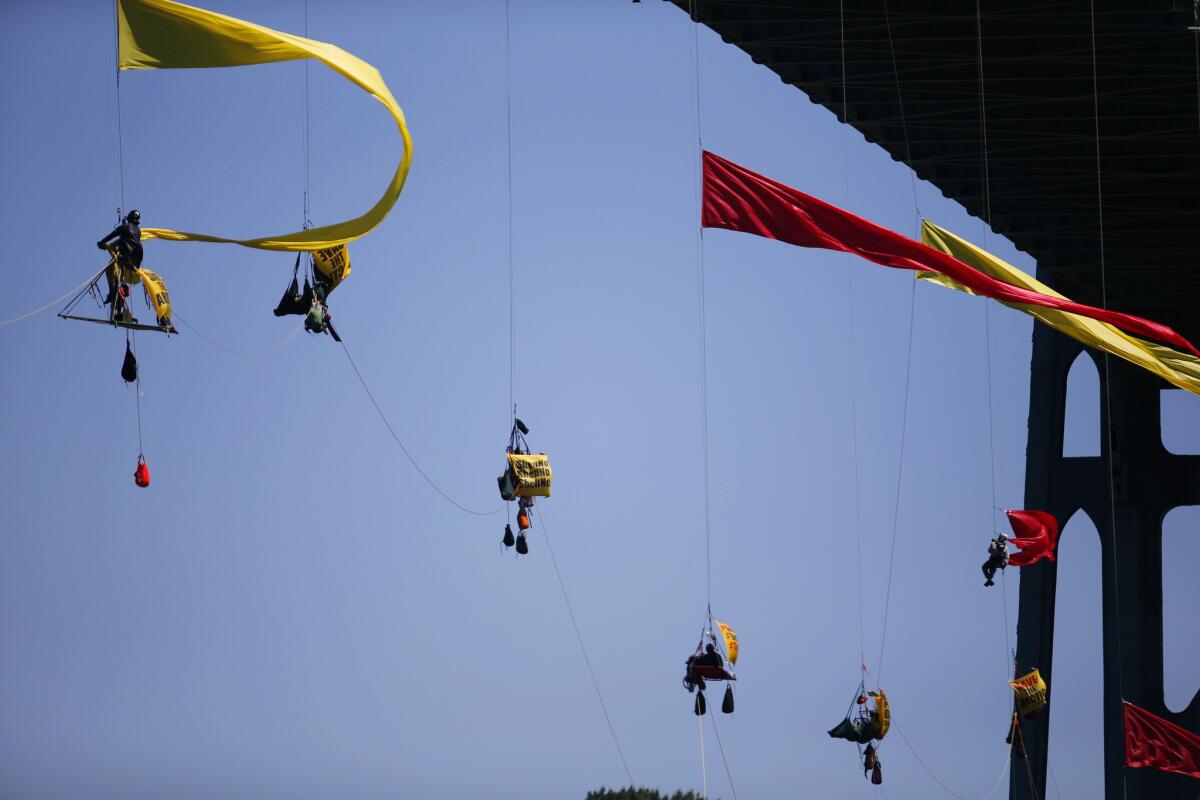 Greenpeace activists hang from the St. Johns Bridge in Portland Ore., to block a Shell vessel that will assist in Arctic oil drilling operations. Law enforcement authorities eventually cleared the protesters, and the vessel headed for the Pacific Ocean.