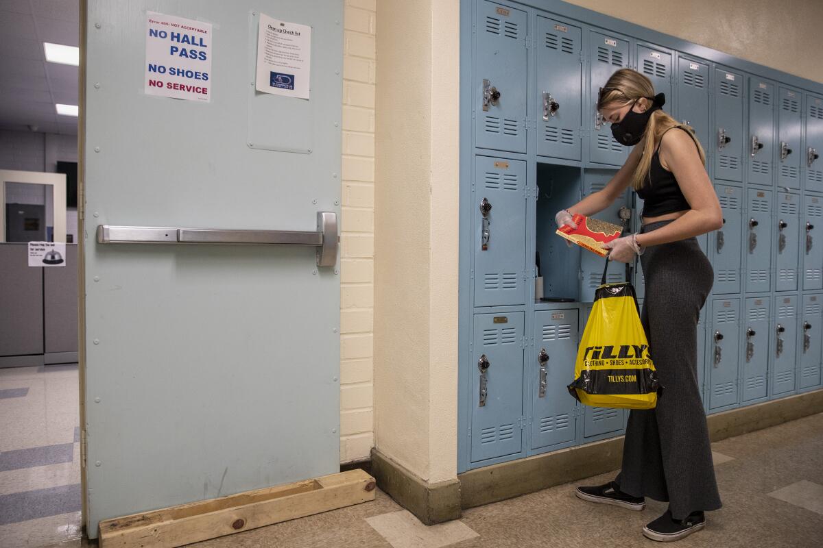 A student wearing a mask at her locker in school