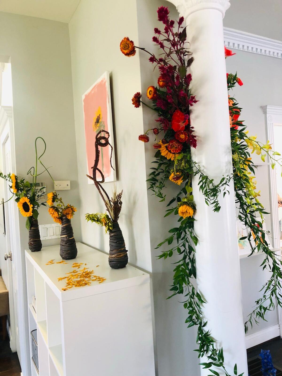 Live floral arrangements by Aubrey Mejia of Fibonacci Florals frame Andrew Alcasid's sunflower painting