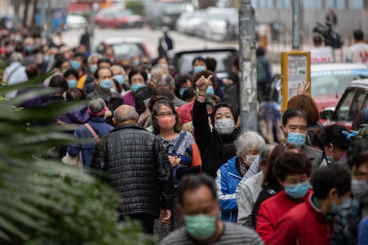 People line up to receive free face masks from a convenience store chain in Hong Kong. The city embraced masks early and has had very few deaths from COVID-19.