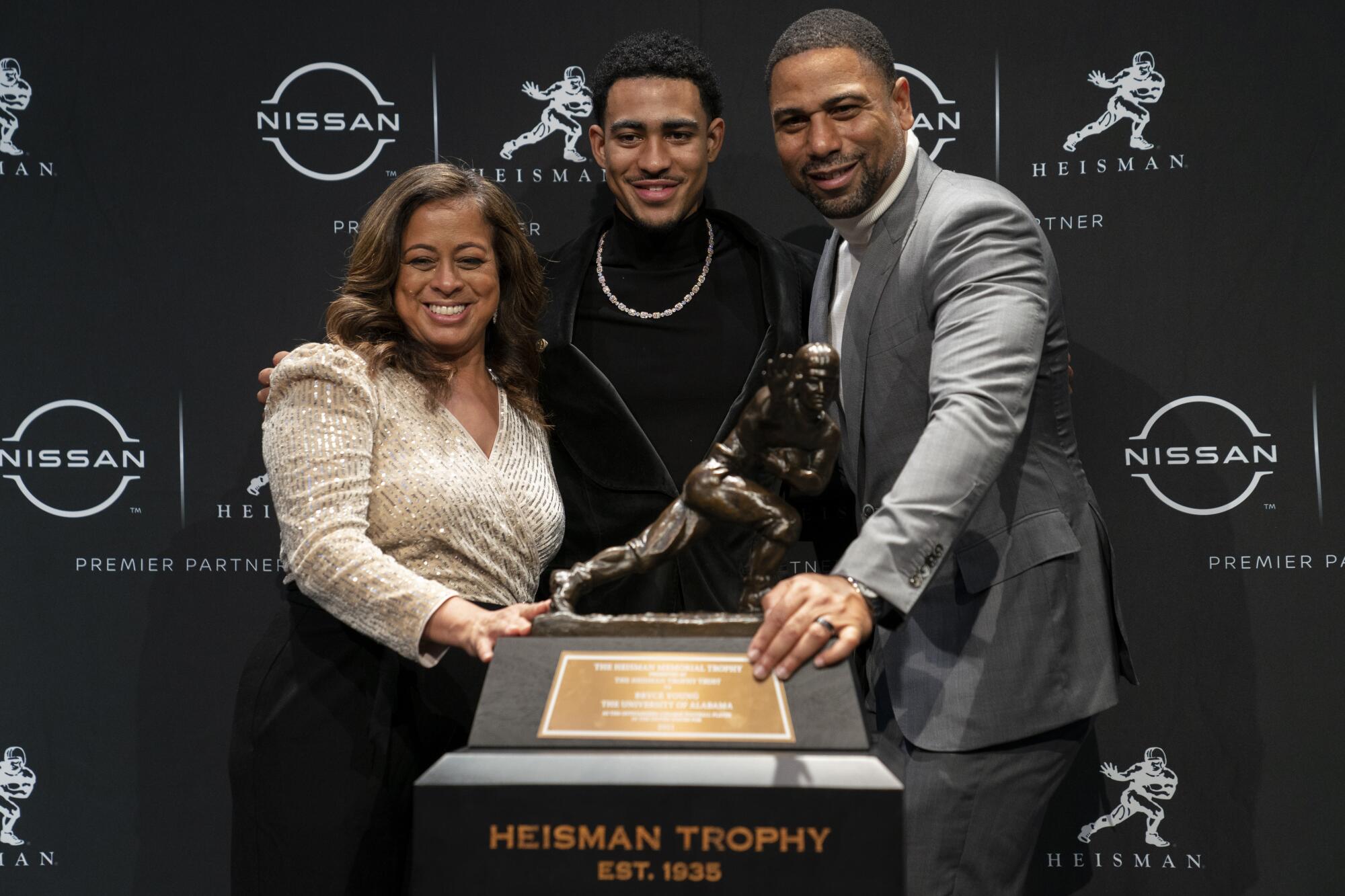 Alabama quarterback Bryce Young poses for a photograph with his parents after winning the Heisman Trophy on Dec. 11, 2021.