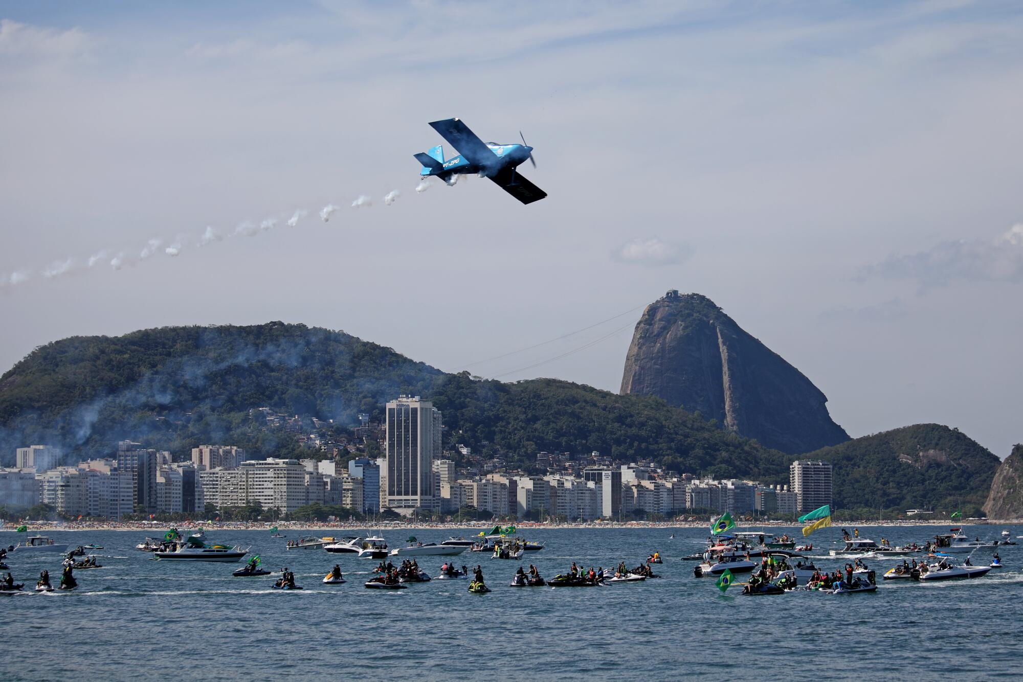 A plane flies over boaters during a rally for the president.