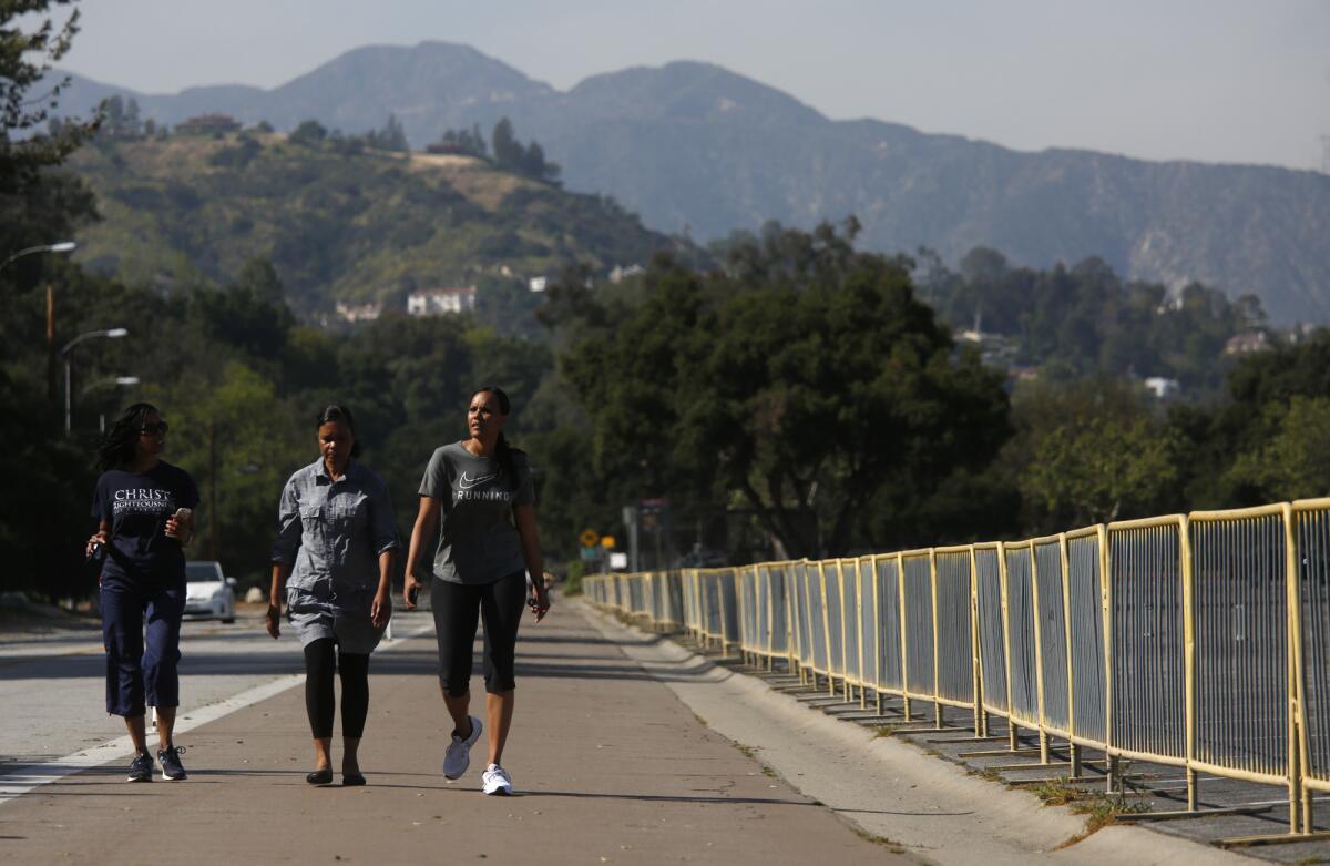 Walkers make their way along West Drive on a walk around the Rose Bowl in Pasadena.