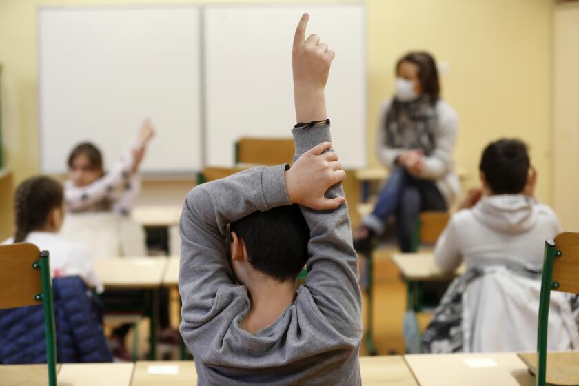FILE - Schoolchildren raise their fingers to answer their teacher Sandrine Albiez, wearing a face masks, in a school in Strasbourg, eastern France, May 14, 2020. The French government is unveiling a new plan on Wednesday Sept.27, 2023 to stop the bullying of children, amid growing concern about suicides by children whose families say they were targeted by bullying online or at school (AP Photo/Jean-Francois Badias, File)