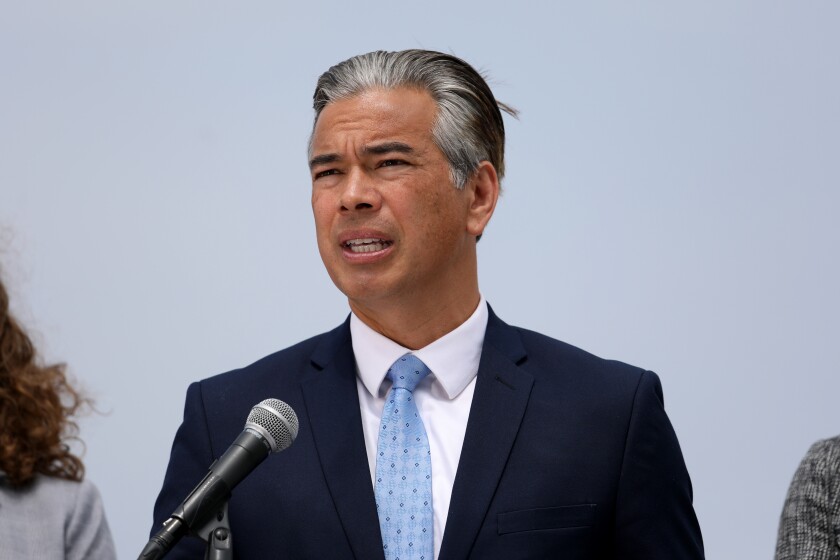 A man in a suit and tie speaks at a microphone