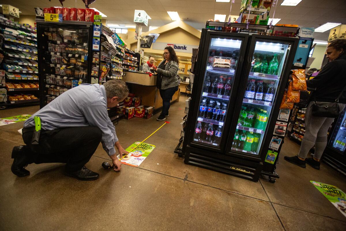 A worker measures the floor at a grocery checkout lane