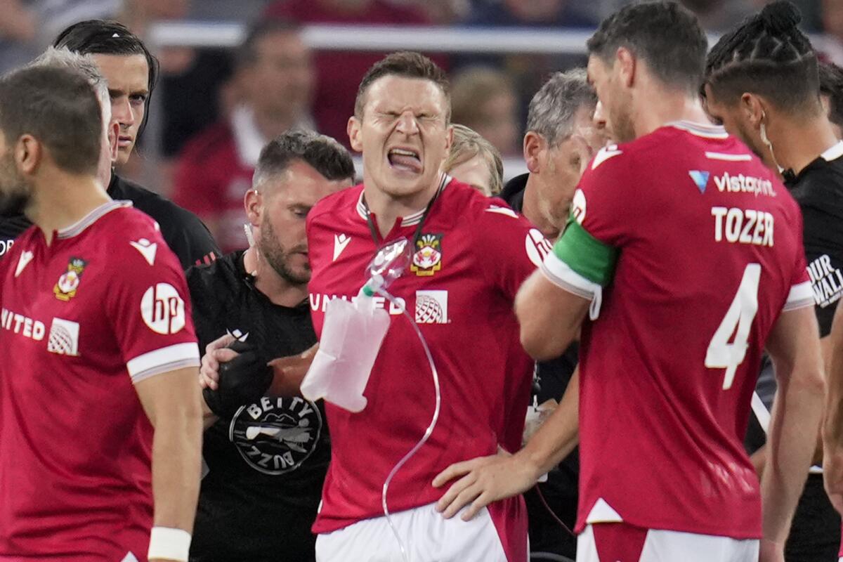 Wrexham striker Paul Mullin, center, grimaces after puncturing his lung