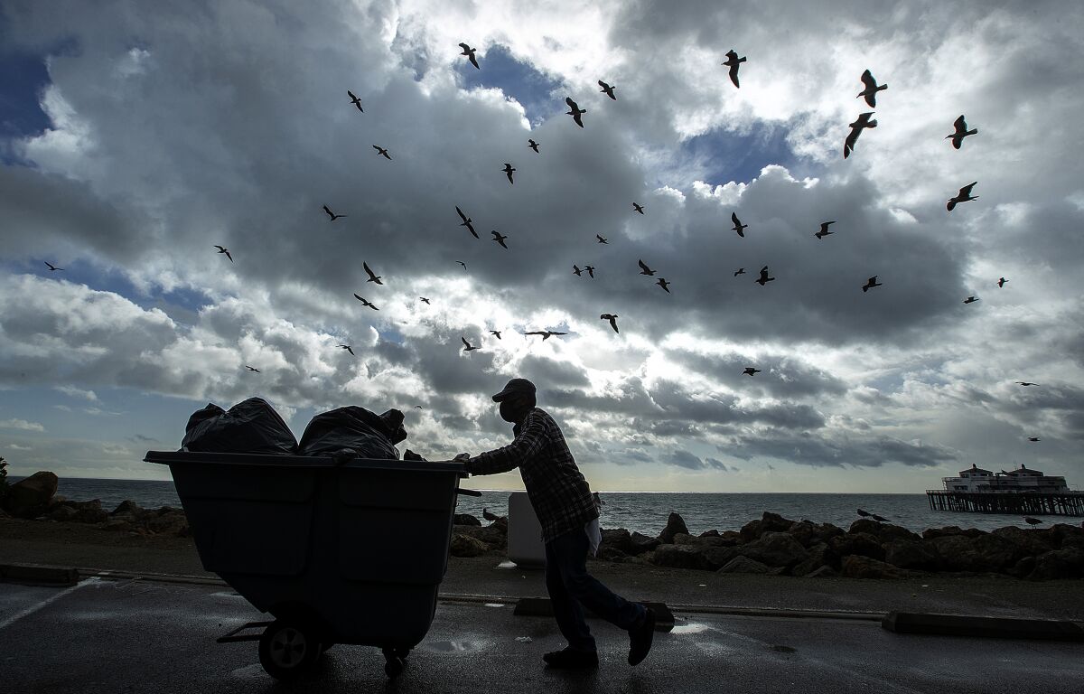 Cervando Lopez Garcia makes his way to a nearby dumpster after collecting trash near the Malibu Pier.
