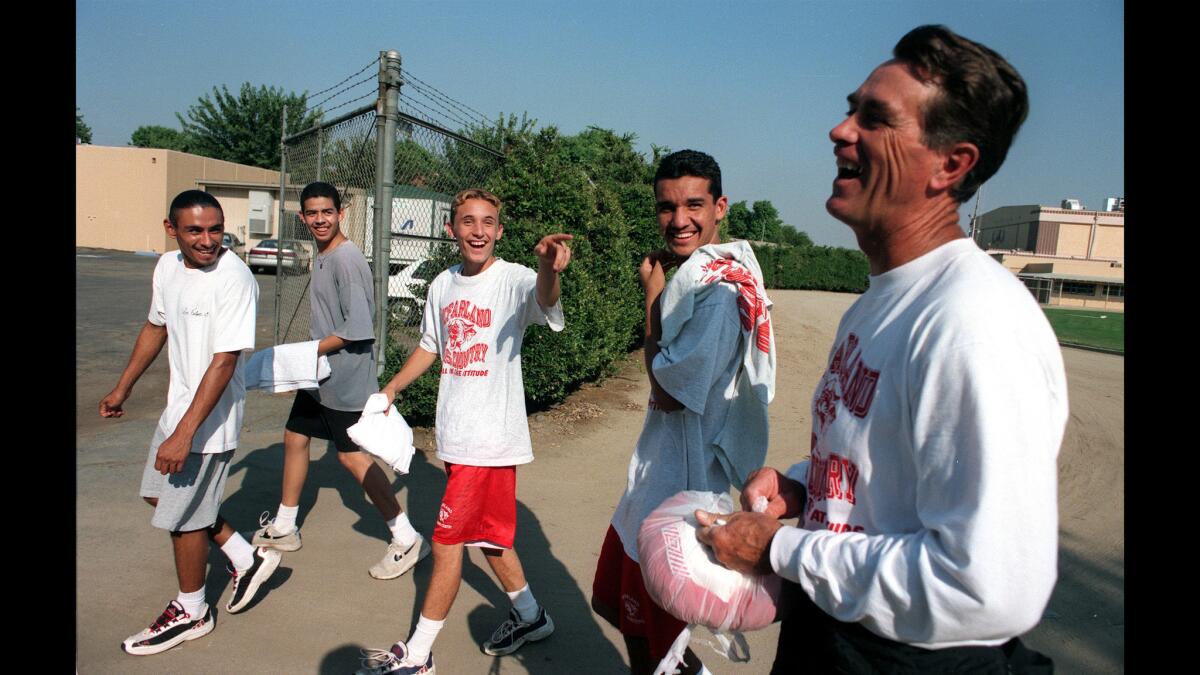 McFarland High cross-country coach Jim White shares a laugh with some team members in 1997, shortly after the team's portrait was taken for the school yearbook.
