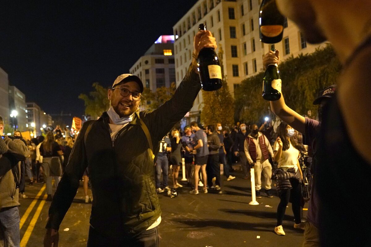 People raise bottles of champagne as they celebrate near the White House in Washington, D.C. 