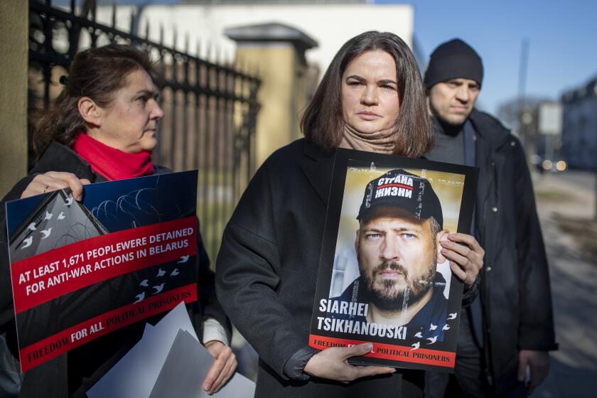 FILE - Belarusian opposition leader Sviatlana Tsikhanouskaya, centre, holds a portrait of her jailed husband Syarhey Tsikhanousky attending a protest demanding freedom for political prisoners in Belarus, in front of the Belarus Embassy, in Vilnius, Lithuania, Friday, March 8, 2024. Belarus’ exiled opposition leader said Thursday, May 2, 2024, that she hasn’t heard from her imprisoned husband for 421 days. (AP Photo/Mindaugas Kulbis, File)