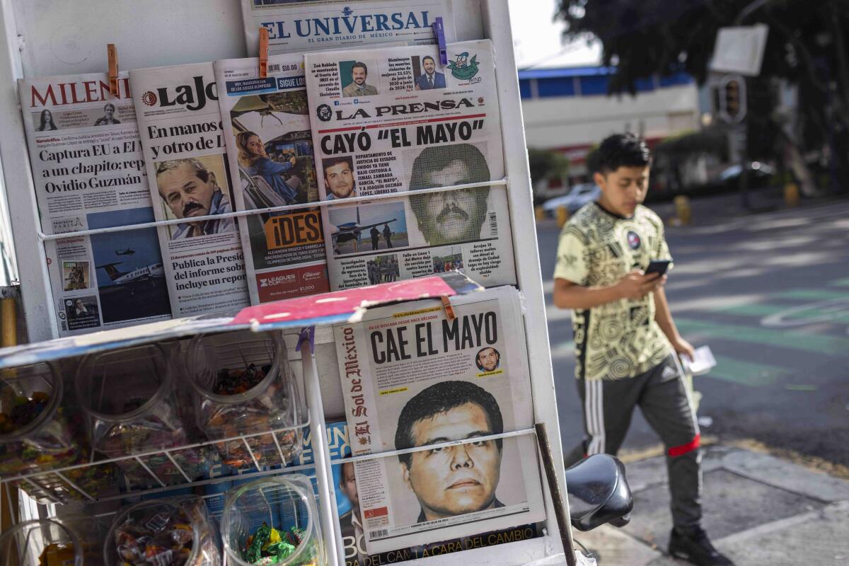 A rack holding various newspapers, with a person walking in the background.