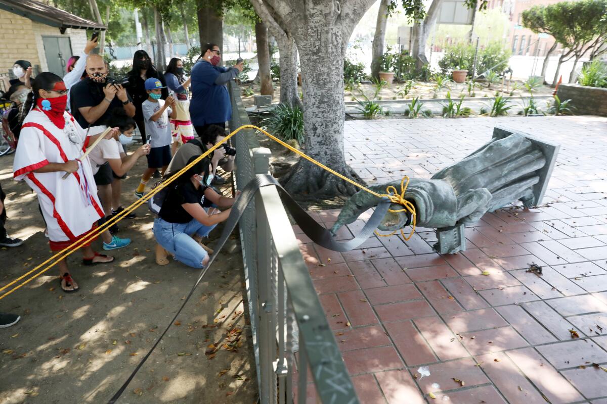 Activists topple the statue of Father Junipero Serra at Father Serra Park in Pueblo Amigo on Saturday.
